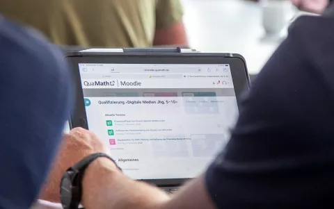 Blick über die Schulter eines Nutzers des QuaMath-Moodle auf einem Tablet.